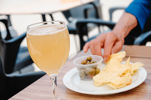 senior woman takes a potato chip from a plate, a Photo by Nito