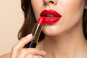 Woman applying bright red lipstick to her lips, a Health & Medical Photo by DanFLCreativo