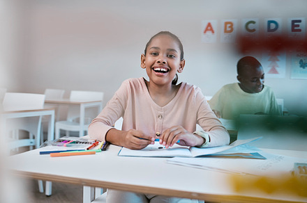 Education, learning and portrait of child with smile in classroom for reading, writing and math in Montessori school. Books, students and happy girl at desk with fun notebook studying for future exam, a Photo by Peopleimages.com