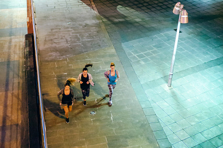 Women friends runners training together on the empty city at night, a Photo by davidpereiras