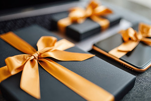 Elegant black gift boxes with orange ribbons and smartphone, a Holiday Photo by AlyaAnd