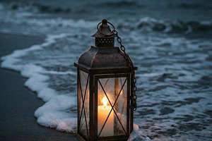 Lit Candle Lantern on Beach, a Nature Photo by Virgo Studio
