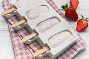 Diy strawberry yogurt popsicles chilling in mold on white wood, a Food & Drink Photo by Olena Rudo