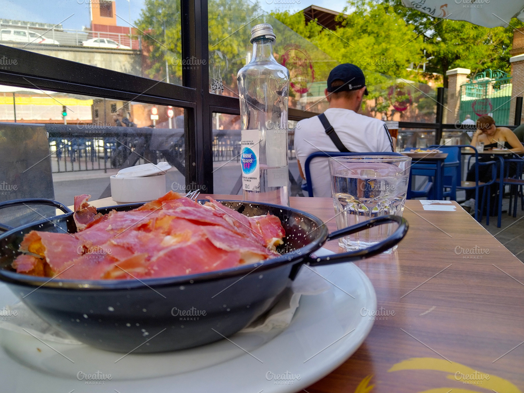 Outdoor café tapas with sliced ham and empty glass, a Food & Drink Photo by DanFLCreativo