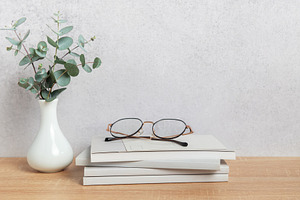 Eucalyptus branches, eyeglasses resting on books, and minimalist, a Background Photo by Olena Rudo
