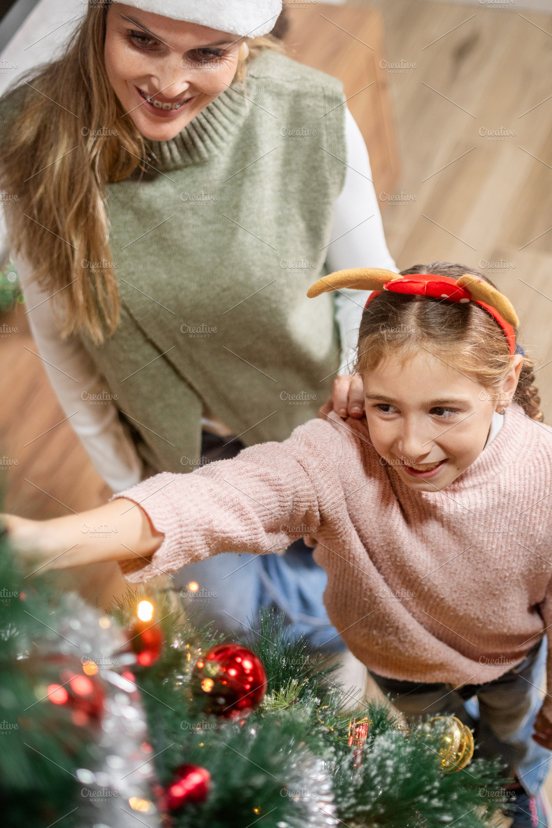 Mother and daughter decorating Christmas tree together at home, a Holiday Photo by etorres69