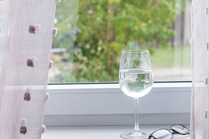 Wine glass and eyeglasses on windowsill in natural light, an Industrial Photo by MDBildes