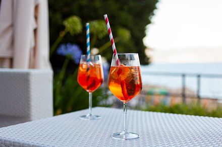 Two aperol spritz on a summer evening in a mediterranean pub, a Food & Drink Photo by Bepslabor