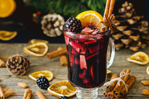 Glass of hot mulled wine for the new year with ingredients for cooking nuts