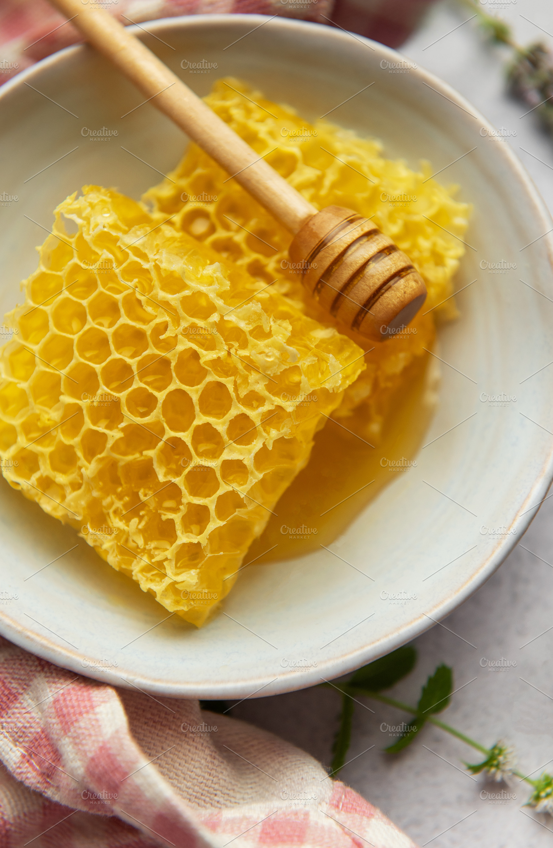 Honeycomb and honey dipper resting in bowl on table, a Food & Drink Photo by Olena Rudo