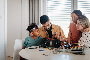 Parents building toy robotic kit, a School & Education Photo by HalfPoint