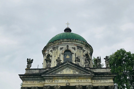 Historic church with ornate pillars and green dome under cloudy sky. Roman Cath, a Photo by AS photostudio