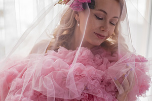 portrait of a fashionable blonde woman in a pink dress and rose flower in her h, a Person Photo by SaulichPhoto