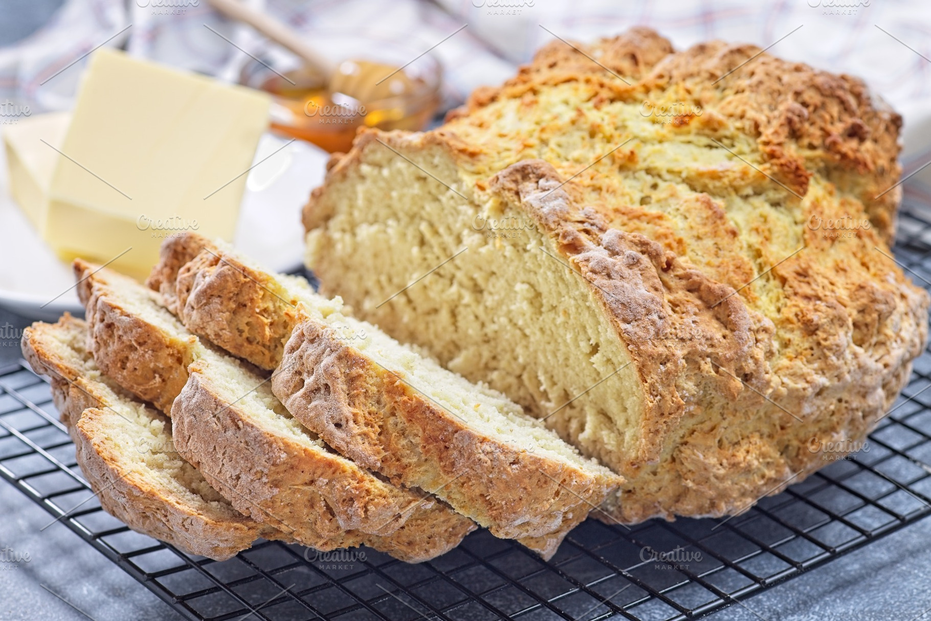 Freshly baked soda bread on cooling rack, sliced, butter and honey in the backg, a Food & Drink Photo by iuliia_n