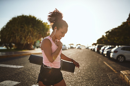 Smiling woman walking to her yoga class listening to music