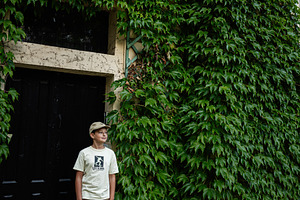 Young boy standing by ivy-covered structure in Lancut, Poland, a Photo by AS photostudio