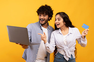 Joyful indian couple with laptop and credit card emotionally reacting to online, a Person Photo by Prostock-Studio
