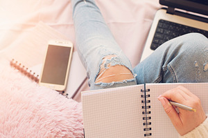 Feminine workplace concept featuring bed, woman, and writing