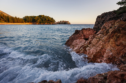 Wide angle seascape view with crashing waves on rocks in sunset light, a Nature Photo by serkum