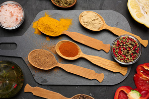 Assorted ground spices in wooden spoons, turmeric, paprika, nutm, a Food & Drink Photo by ndanko
