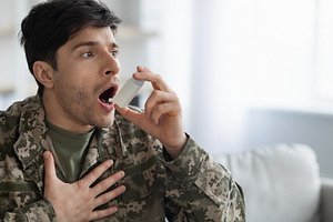 Military man suffering from panic attack, using inhaler, a Photo by Prostock-Studio