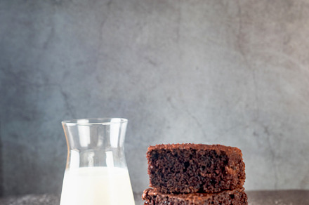 A stack of chocolate brownies on bakery paper and glass of milk, a Food & Drink Photo by vimart