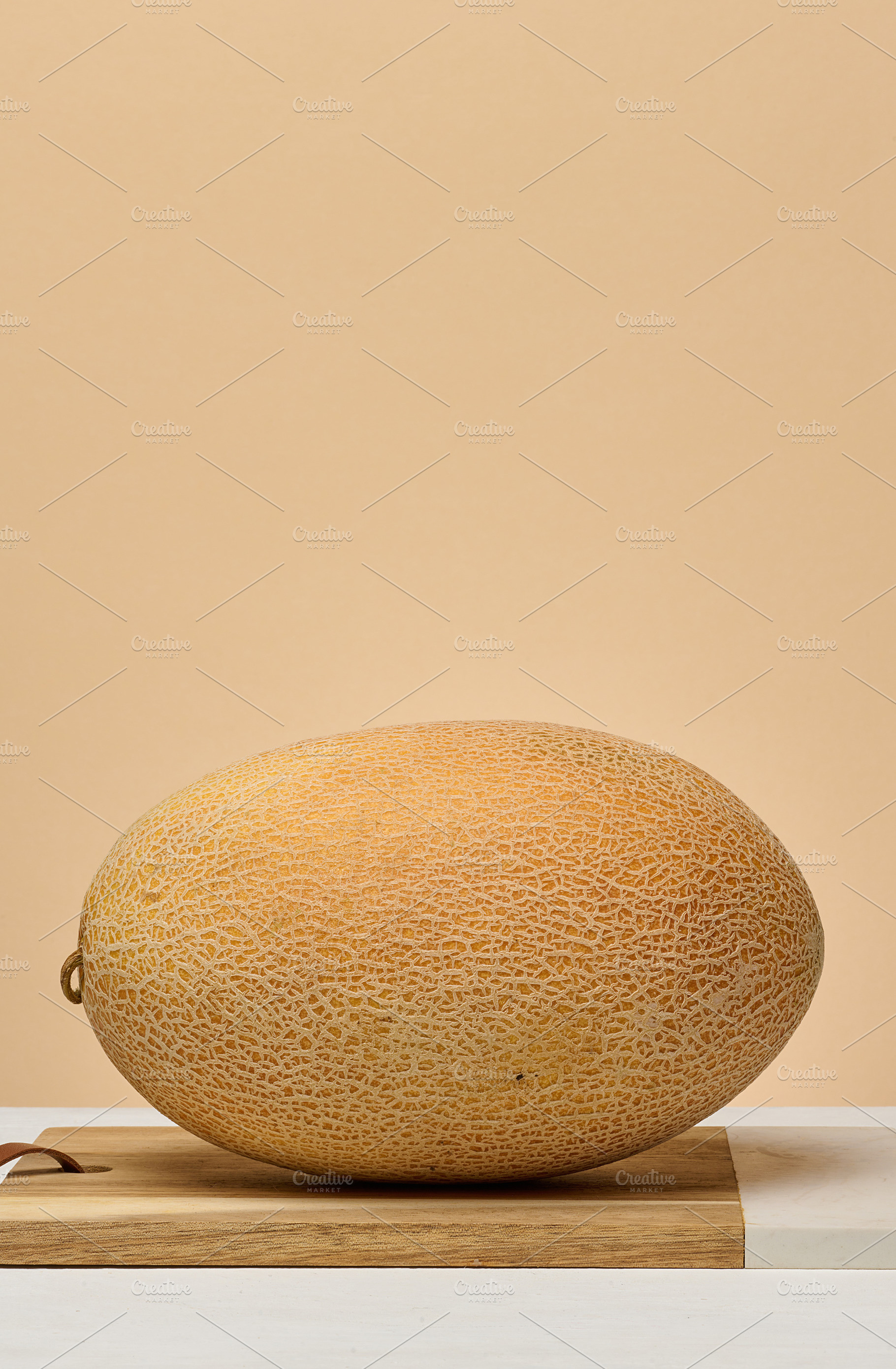 Whole cantaloupe melon on white table, beige background, a Food & Drink Photo by ndanko