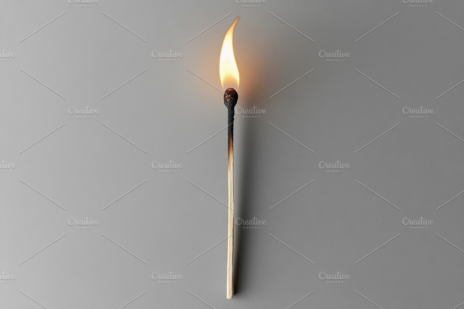 Ignited matchstick on grey background, a Photo by AlyaAnd