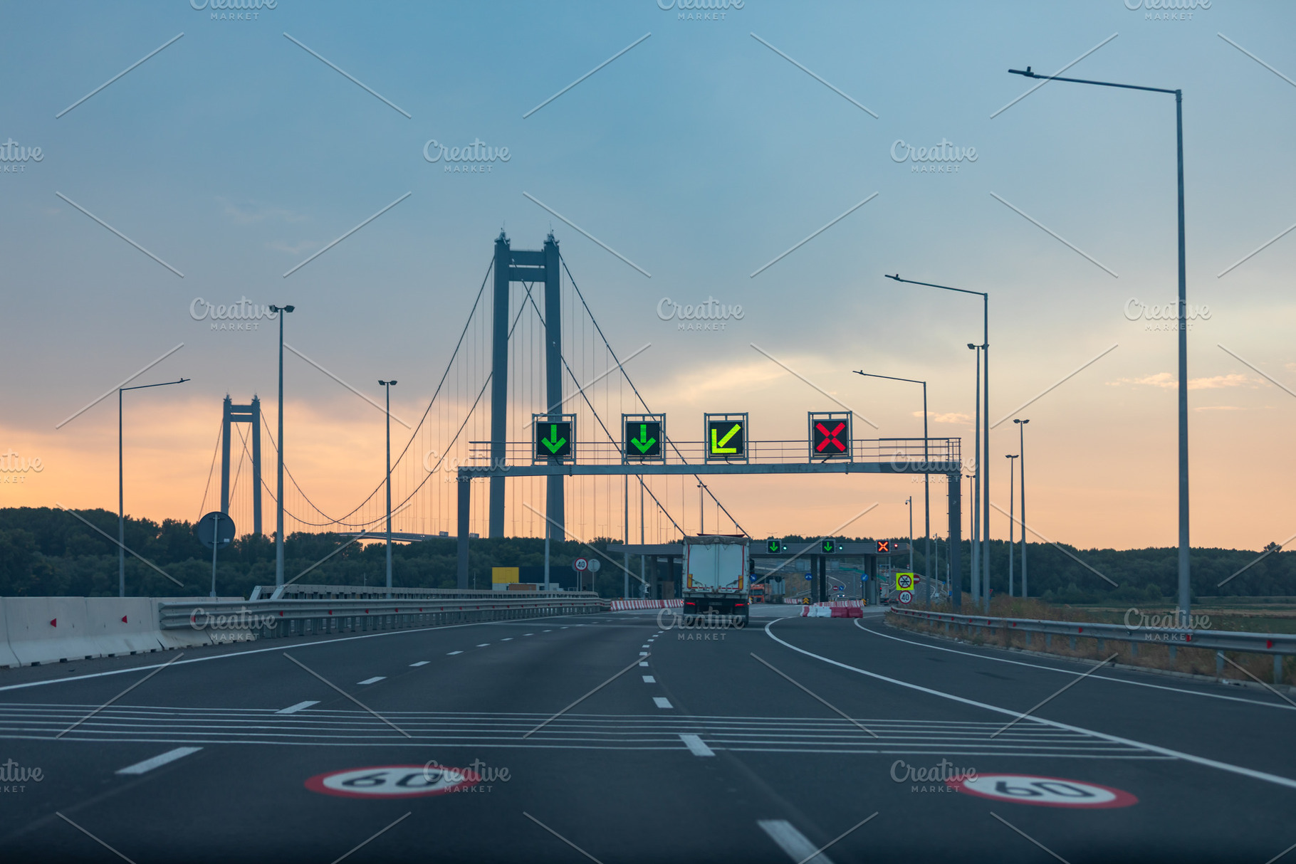 Empty highway leading to a large suspension bridge at dusk with illuminated lan, a Transportation Photo by Ales Munt