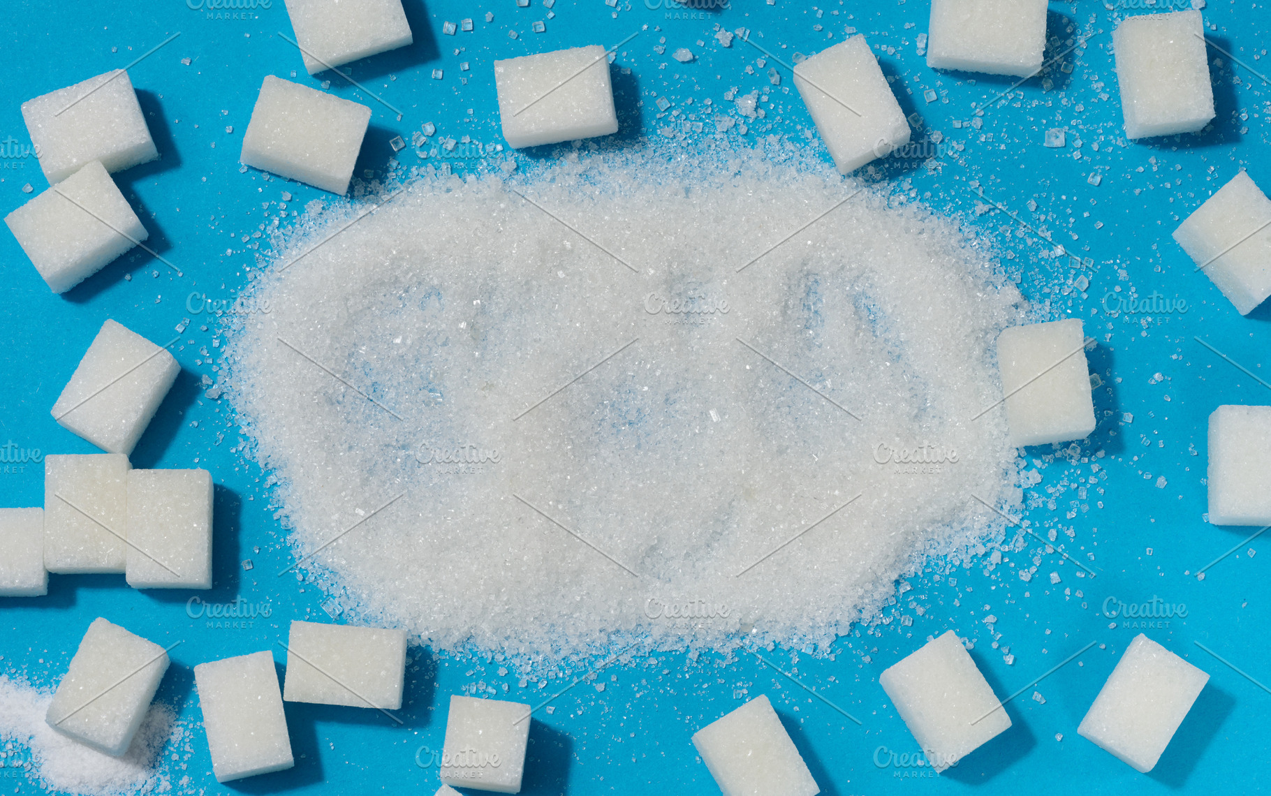 Scattered white granulated sugar surrounded by refined sugar cub, a Food & Drink Photo by ndanko