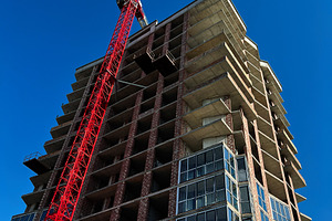 Modern urban building construction with crane under a clear blue sky, a Photo by AS photostudio