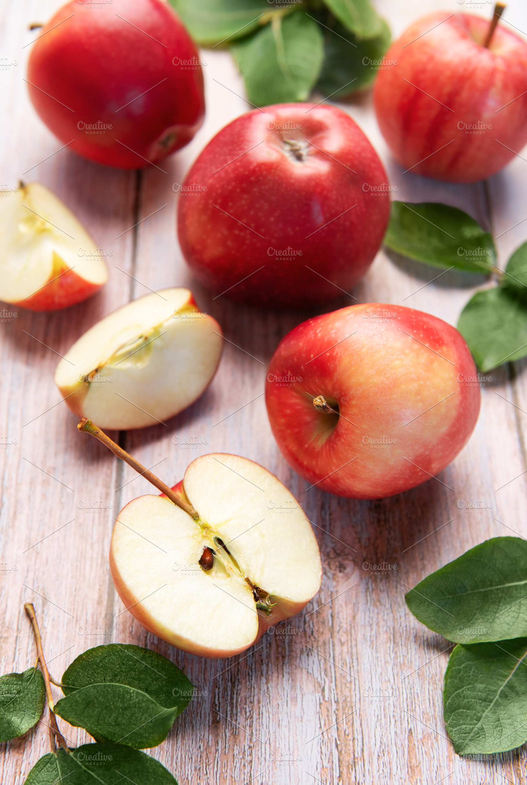 Red apples and slices on light wood background, a Food & Drink Photo by Olena Rudo