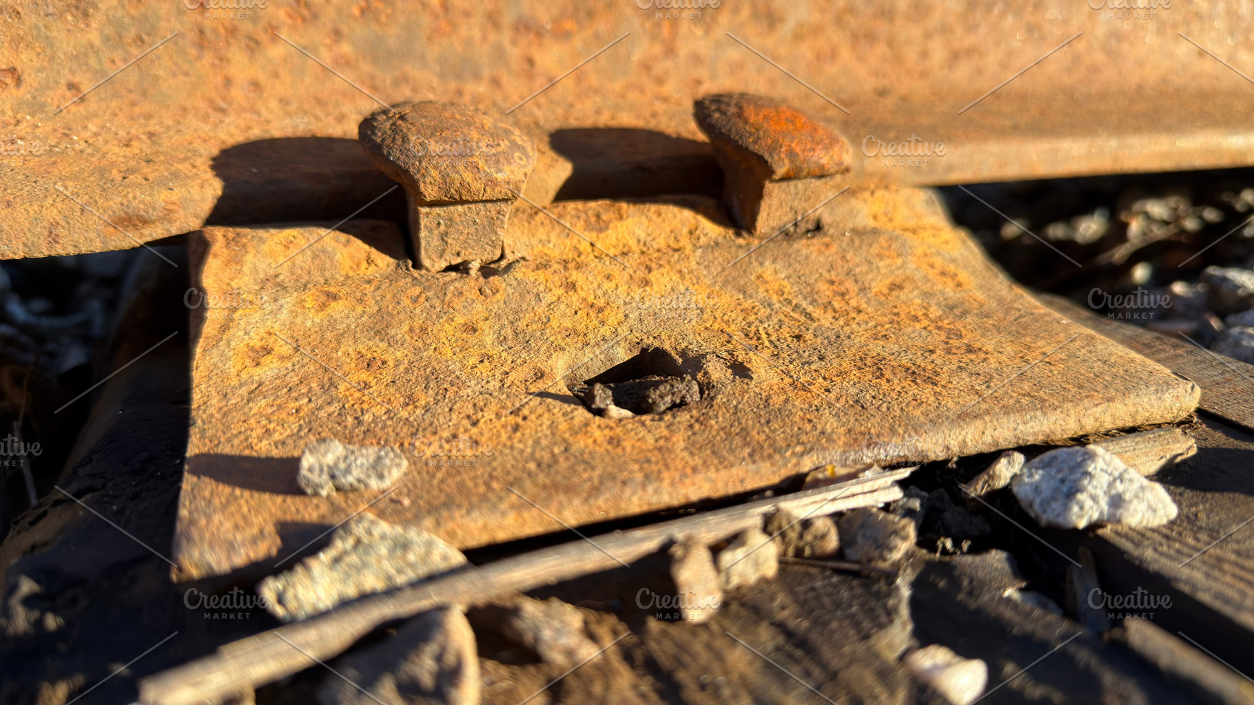 Close-up of rusty railroad track components on gravel, an Industrial Photo by Textures & Backgrounds