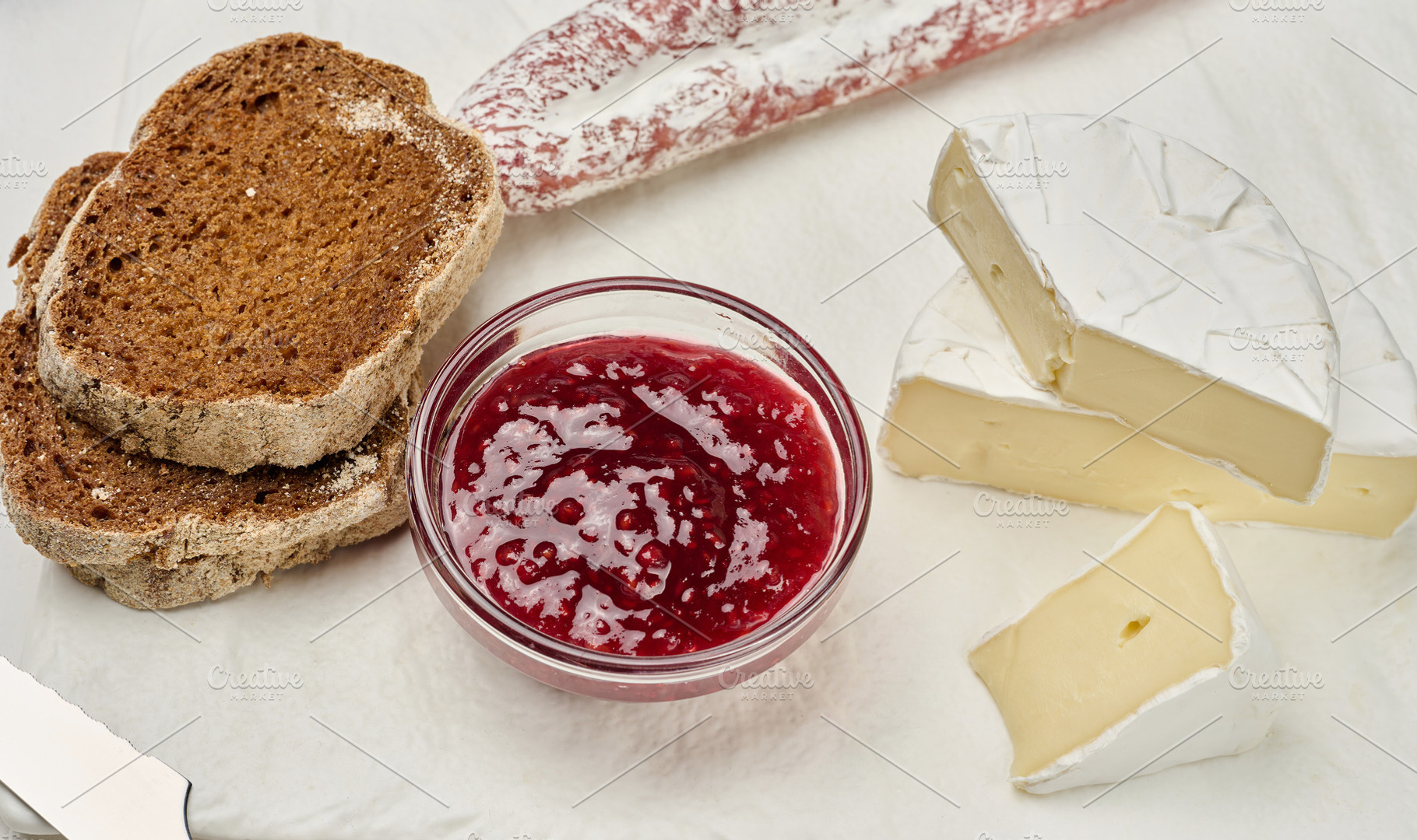 Sliced round head of Camembert cheese on a white board and, a Food & Drink Photo by ndanko