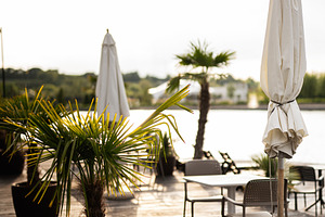 Outdoor patio with chairs, umbrellas, and planters near a scenic water view, a Photo by AS photostudio