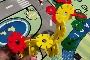 Colorful construction toy pieces on play mat decorated with cityscape streets, a Photo by AS photostudio