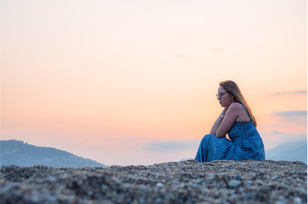 Woman sits on the beach and looks at, a Person Photo by Jan Jack Russo Media