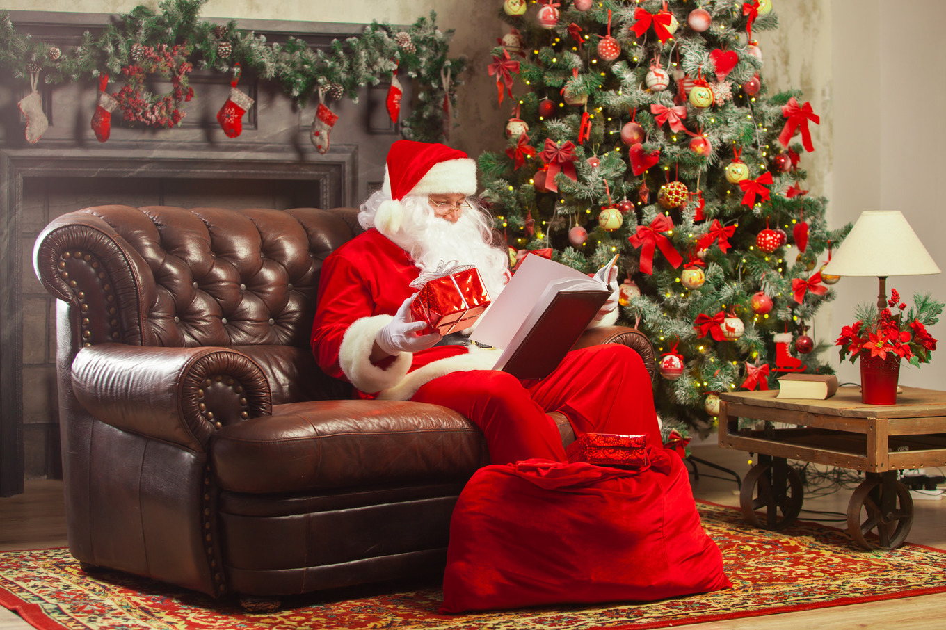 Santa Claus sitting at his home in a comfortable chair and reading