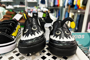 Colorful stylish children's shoes displayed on shelf in a retail clothing store, a Photo by AS photostudio