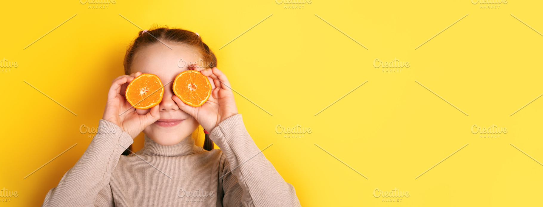 Smiling girl holding orange halves over her eyes against vibrant, a Person Photo by Ales Munt