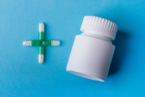 White medicine bottle and green capsule cross on blue background. Concept for h, a Health & Medical Photo by Ales Munt