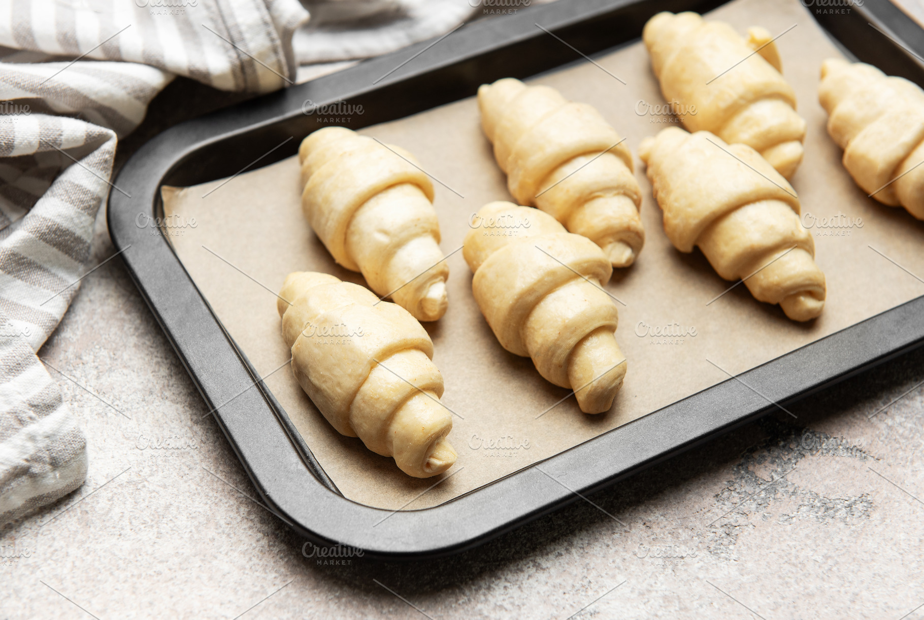 Raw croissants waiting to be baked on baking sheet with baking p, a Food & Drink Photo by Olena Rudo