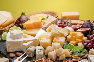 Variety of sliced cheeses with fruits, mint, nuts and cheese cut, a Food & Drink Photo by Volff