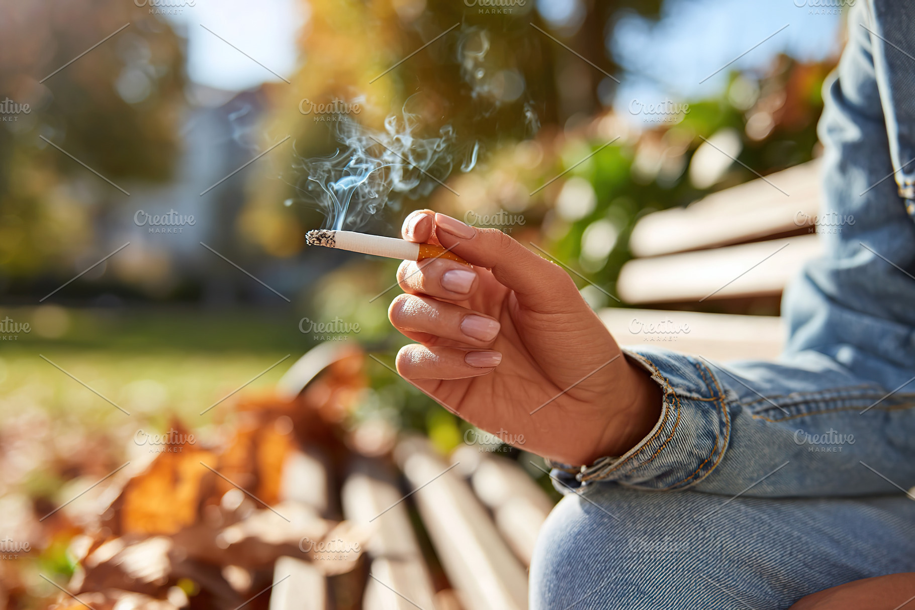 Smoker relaxing on a park bench surrounded by autumn leaves in a sunny afternoo, a Photo by AlyaAnd