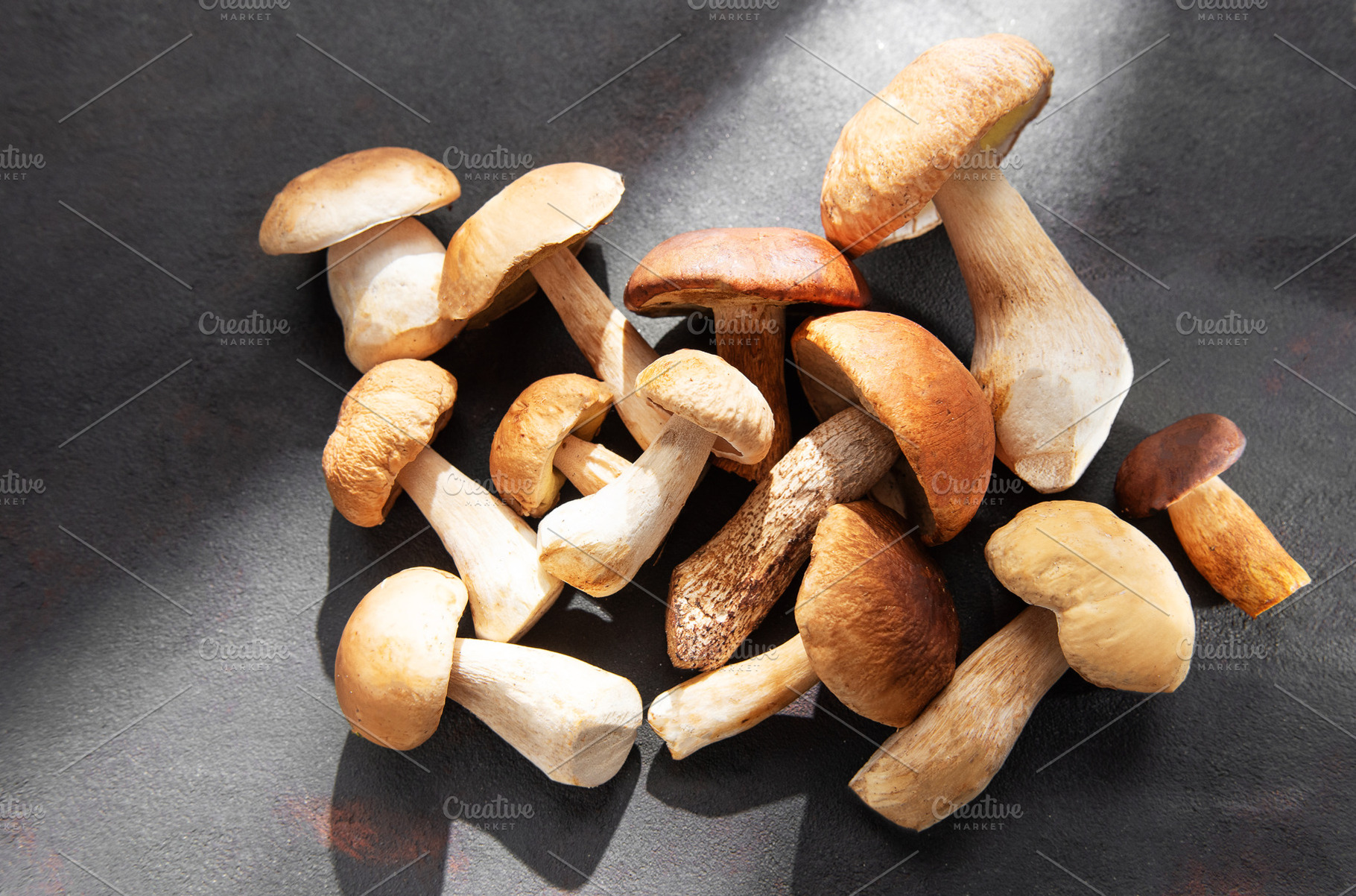 Fresh porcini mushrooms on dark surface ready for cooking, a Food & Drink Photo by Olena Rudo