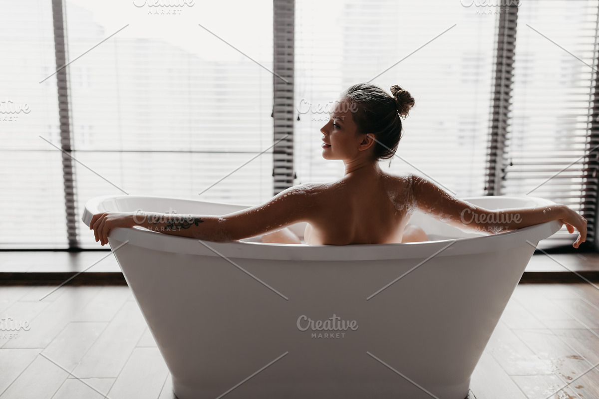 Back view of young lady taking foamy bath, looking aside at free space at home, a Photo by Prostock-Studio (Photo 2 of 2)