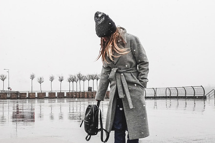 A young woman is walking in the snow in the city.