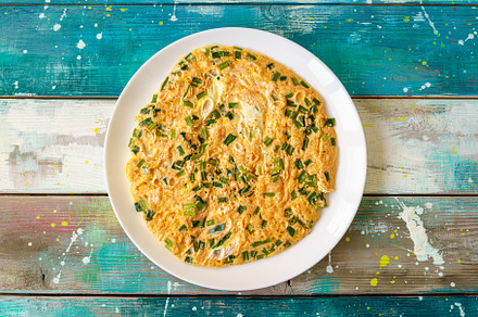 Fluffy omelet with fresh chives on a white plate. Delicious egg dish for breakf, a Food & Drink Photo by Eugene_Photo