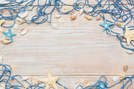 Fishing net, starfishes and seashells framing rustic wooden back