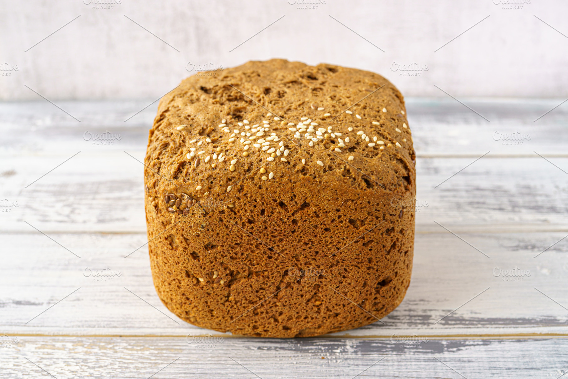 Whole grain bread loaf with sesame seeds and flax seeds on a rustic wooden tabl, a Food & Drink Photo by Eugene_Photo